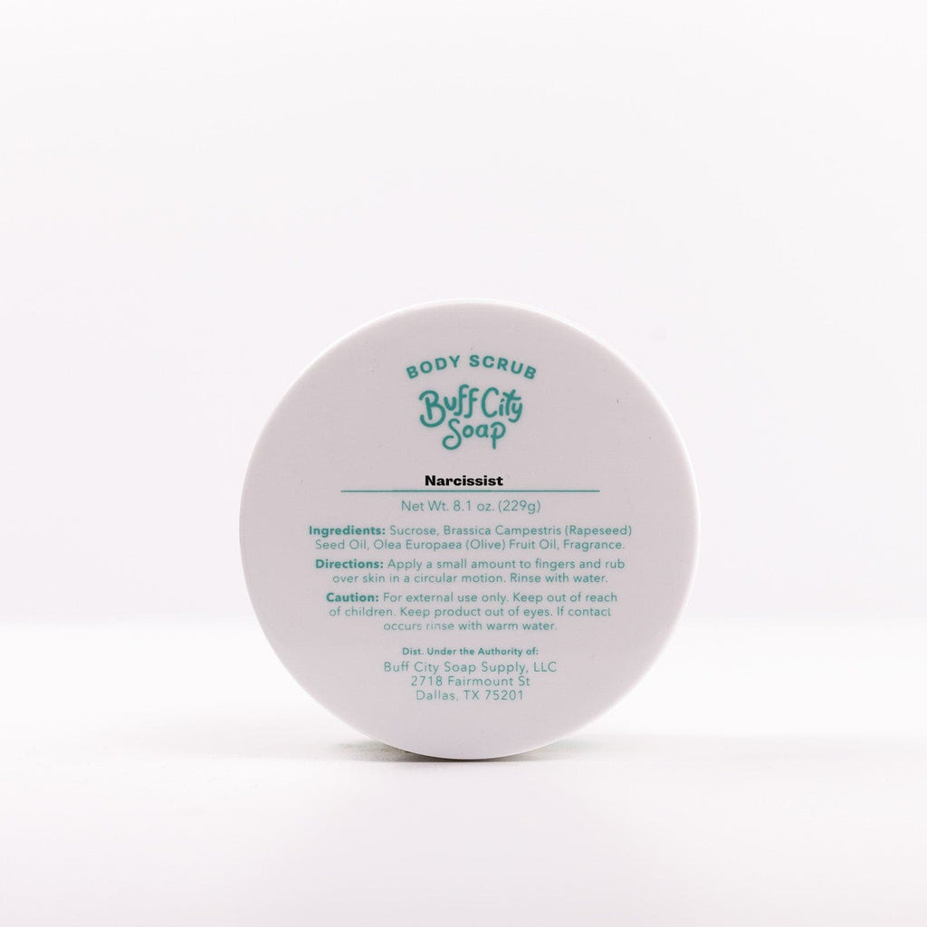 Narcissist Body Scrub placed on side with view of label listing ingredients and directions on lid