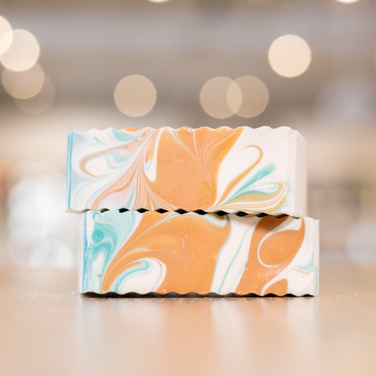 Two Narcissist Soap Bars with white, teal, orange design stacked on each other